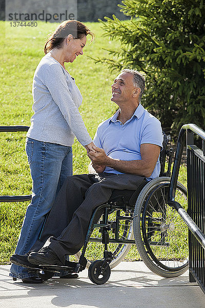 Frau hält Händchen mit Mann im Rollstuhl mit Rückenmarksverletzung auf zugänglicher Rampe