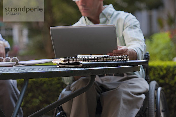 Geschäftsmann mit Rückenmarksverletzung arbeitet an einem Laptop