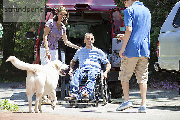 Ein Mann mit einer Rückenmarksverletzung steigt aus einem behindertengerechten Transporter aus  um seine Familie zu besuchen