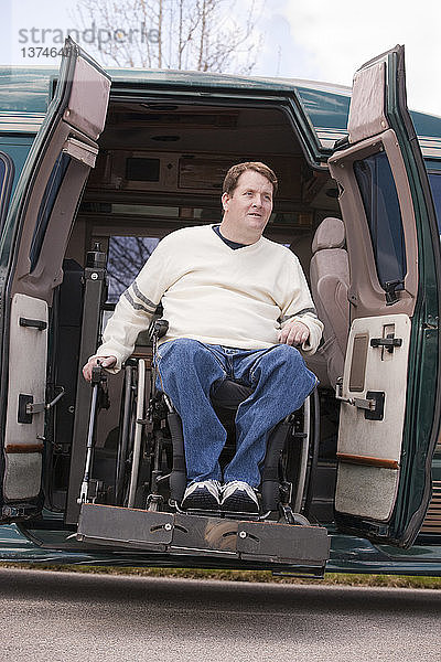 Mann mit Rückenmarksverletzung im Rollstuhl  der aus einem rollstuhlgerechten Lieferwagen aussteigt