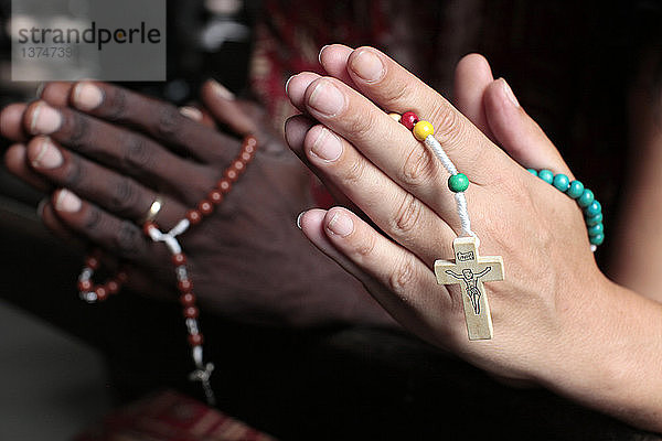 Afrikaner beim Beten des Rosenkranzes. Mann und Frau beten zusammen in einer Kirche.