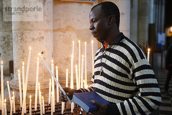 Mann betet mit Kerzen in der Kirche