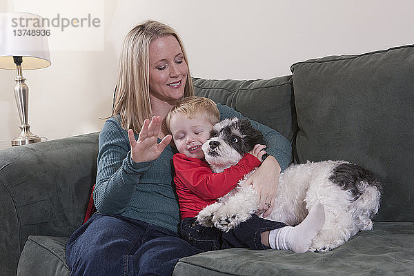 Frau gebärdet das Wort ´Puppy´ in amerikanischer Zeichensprache  während ihr Sohn einen Hund umarmt