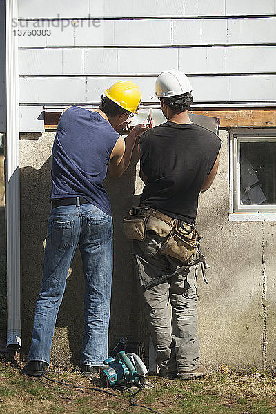 Spanische Zimmerleute  die Abdeckungen unter den Schindeln eines Hauses anbringen