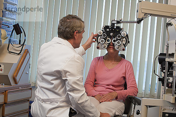 Augenarzt untersucht die Augen einer Frau mit einem Phoropter