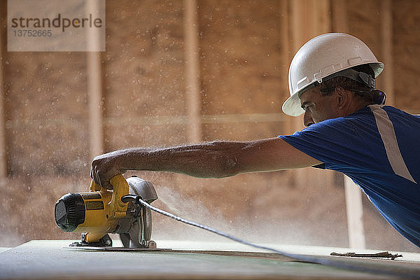 Ein spanischer Zimmermann arbeitet mit einer Kreissäge an der Dachschalung eines im Bau befindlichen Hauses