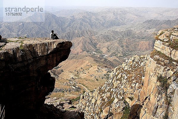 Mann sitzt auf einem Felsen in Halmlam  Halmlam  Jemen.