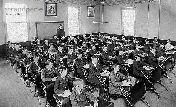 Vereinigte Staaten: um 1895 Fast fünfzig Jungen sitzen aufmerksam an ihren Tischen in einem Klassenzimmer.