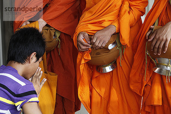 Mann betet nach einer Almosengabe an Mönche