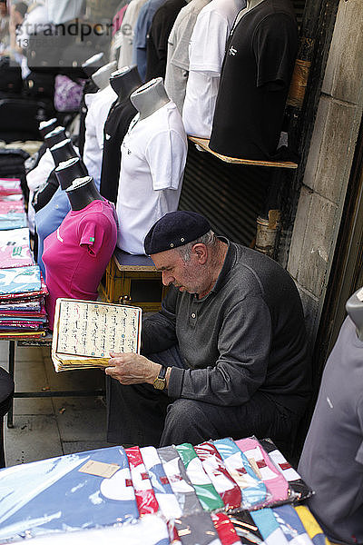 Ladenbesitzer auf dem Grand Bazar liest islamische Schriften