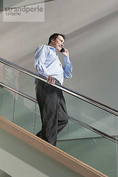 Geschäftsmann  der mit seinem Handy telefoniert und eine Treppe hinuntergeht