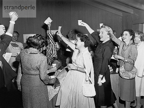 Vereinigte Staaten: um 1955 Eine Gruppe von Frauen bei einer Versammlung  die jubelnd ihre Gläser erhebt und anstößt.