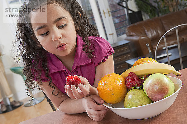 Hispanisches Mädchen isst eine frische Erdbeere