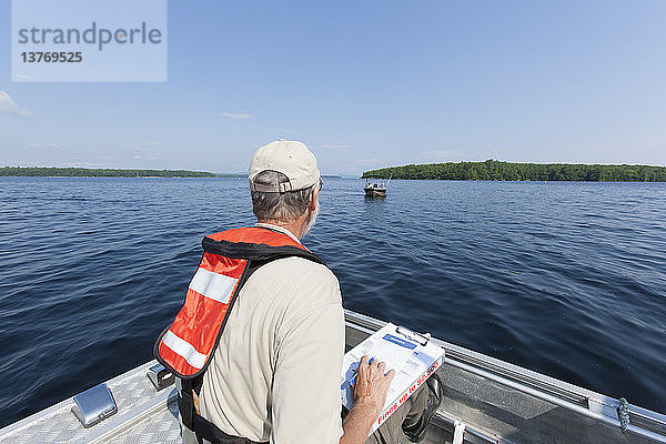 Ein Bauingenieur auf einem Dienstboot bereitet sich auf die Entnahme von Wasserproben aus dem Stausee vor