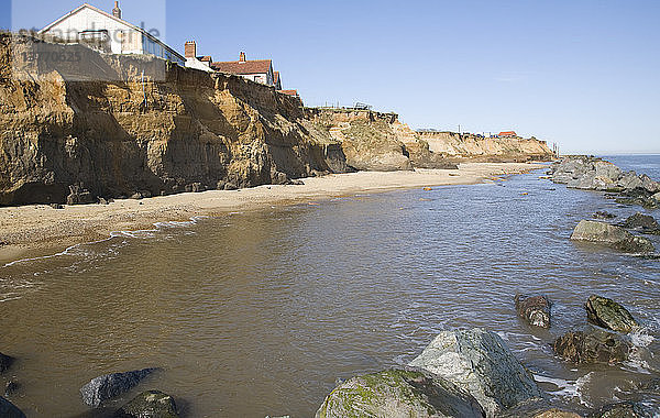 Von der Küstenerosion bedrohte Gebäude auf der Klippe  Happisburgh  Norfolk  England Felsblöcke als Schutzmaßnahmen