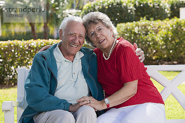 Älteres Paar mit Arm um sitzen auf einer Parkbank
