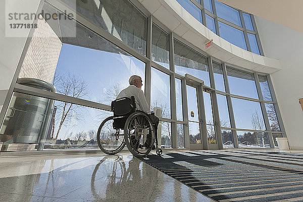 Arzt mit Muskeldystrophie im Rollstuhl am Krankenhauseingang
