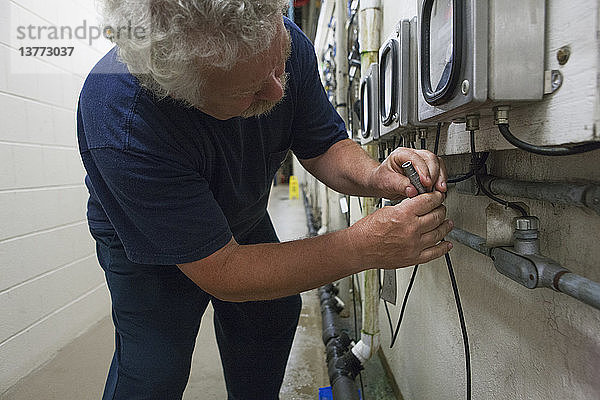 Ingenieur  der das Kabel der elektrochemischen O2-Sonde mit dem Messgerät in einer Wasseraufbereitungsanlage verbindet