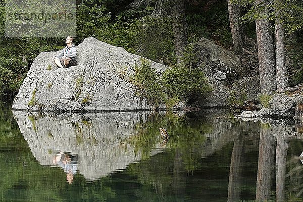 Ein Mann betet vor einem See.