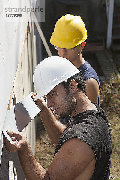 Spanische Zimmerleute bei der Installation von Abdeckungen unter Abstellgleisen beim Hausbau