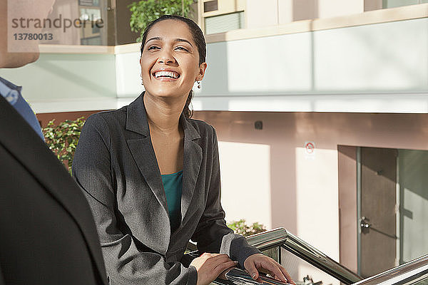 Geschäftspaar lächelnd im Treppenhaus eines Bürogebäudes