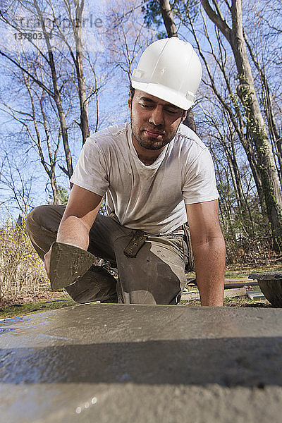 Ein spanischer Zimmermann glättet mit einer Kelle den Beton für das Fundament einer Treppe