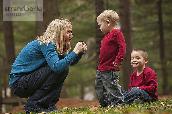 Frau gebärdet das Wort ´Hurt´ in amerikanischer Zeichensprache  während sie mit ihrem Sohn in einem Park kommuniziert