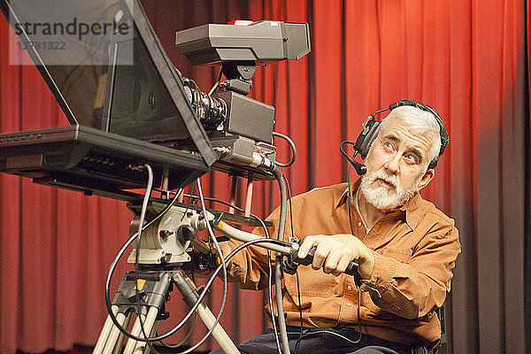 Mann im Rollstuhl mit Muskeldystrophie benutzt eine Fernsehkamera und einen Teleprompter im Studio