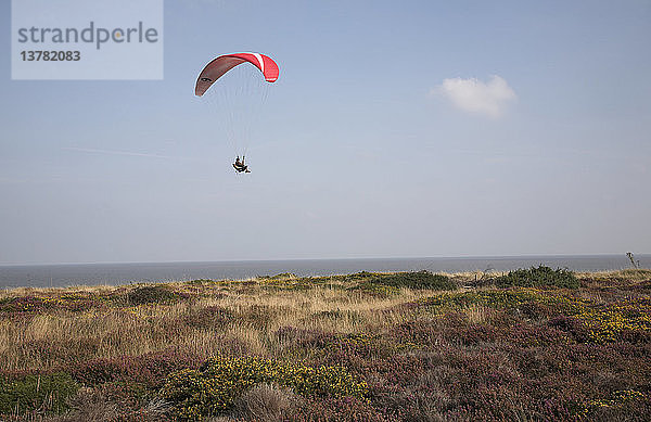 Parasailing über Dunwich Heath  Suffolk  England. Nutzen Sie die Thermik  die von der Klippe unter Ihnen aufsteigt  um an der Küste entlang zu gleiten