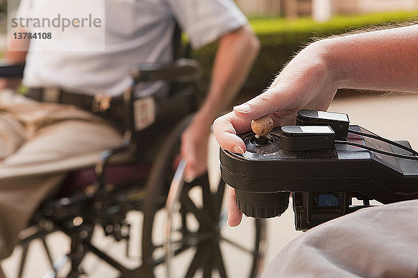 Mann mit Duchenne-Muskeldystrophie steuert einen motorisierten Rollstuhl mit degenerierten Händen