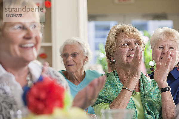 Ältere Frauen klatschen bei einem Mittagessen