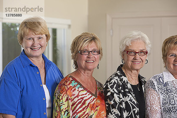 Porträt von vier älteren Freundinnen  die zusammen lächeln