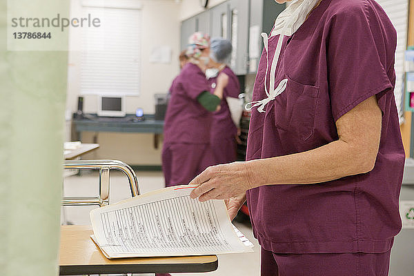 Krankenschwester  die einen medizinischen Bericht nach einer Operation prüft