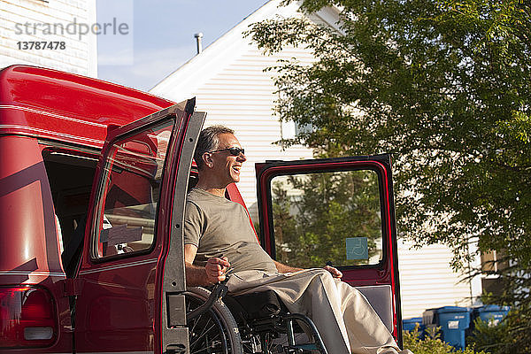 Mann im Rollstuhl wird aus zugänglichem Lieferwagen heruntergelassen