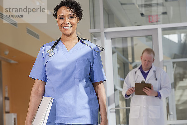 Porträt einer lächelnden Krankenschwester  hinter der ein männlicher Arzt steht