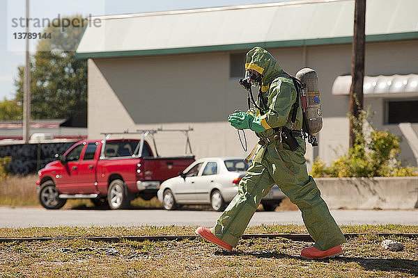 HazMat-Feuerwehrmann geht mit einer Kamera durch ein Feld