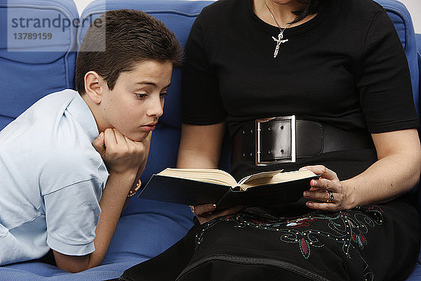 Junge liest mit seiner Mutter in der Bibel