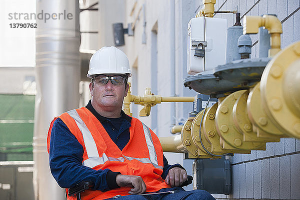 Gebäudetechniker im Rollstuhl bei der Inspektion einer Gasleitung