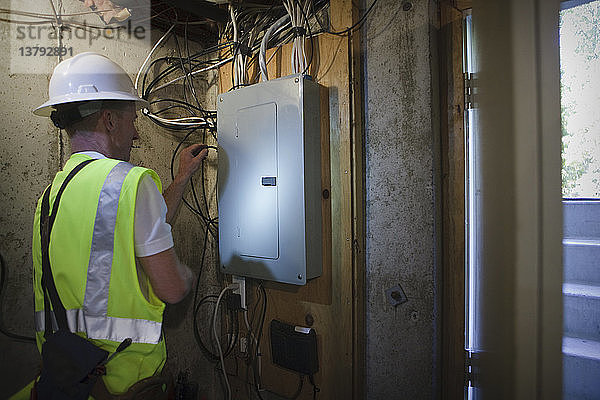 Kabelinstallateur bei der Arbeit an der Stromtafel im Keller eines Hauses