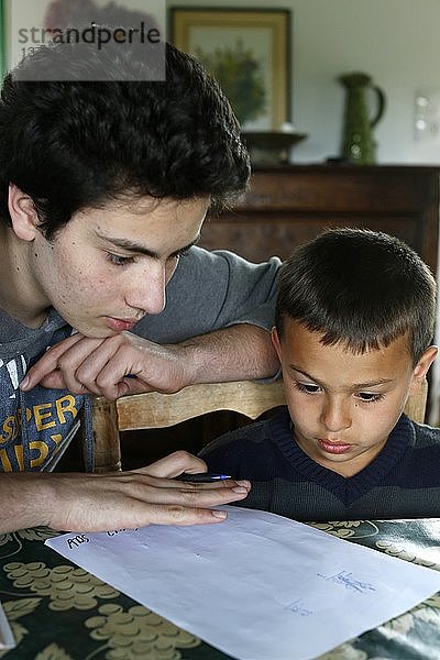 Ein Teenager hilft seinem Bruder bei den Hausaufgaben.