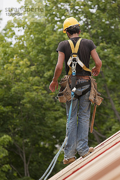 Hispanischer Zimmermann bei der Arbeit an der Dachkonstruktion eines Hauses