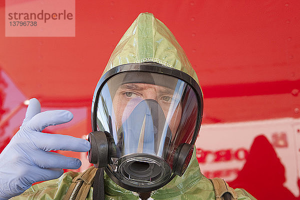 Nahaufnahme eines HazMat-Brandbekämpfers  der den Luftregler der Maske einstellt