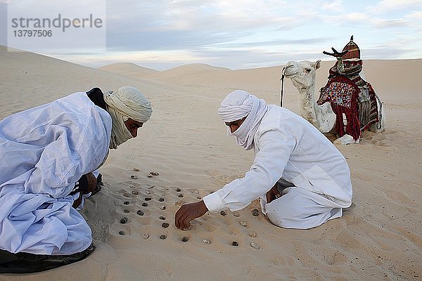 Beduinen spielen mit Steinen im Sand.