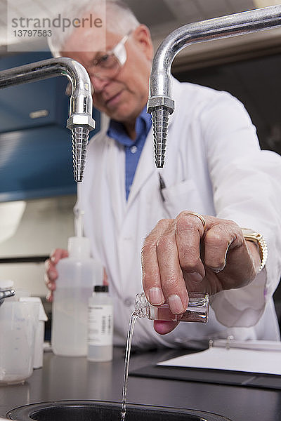 Wissenschaftlerin beim Ausgießen von Flüssigkeiten aus einer Probenflasche im Labor einer Wasseraufbereitungsanlage