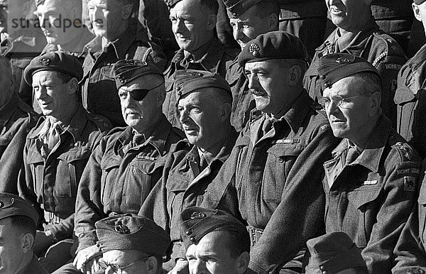 Eine Gruppe von Militärangehörigen. Blick nach vorn für ein formelles Truppenfoto. Sie tragen formelle Uniformen und Kopfbedeckungen. Ein Mann trägt eine Augenklappe. Veteranen bei einer Wiedervereinigung.