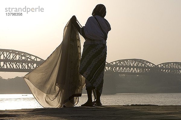 Frau entfaltet einen Sari entlang des Flusses Ganga  Varanasi  Indien.