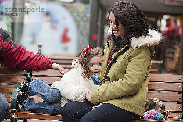Mädchen sitzt mit seiner Mutter auf einer Bank