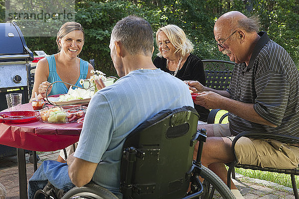 Mann mit Rückenmarksverletzung im Rollstuhl beim Familienpicknick mit den Großeltern