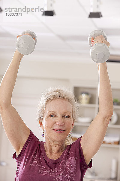 Porträt einer älteren Frau  die mit Hanteln in einem Fitnessstudio trainiert