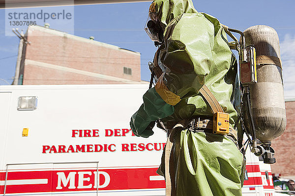 HazMat-Feuerwehrmann mit Drucklufttank und Löschfahrzeug